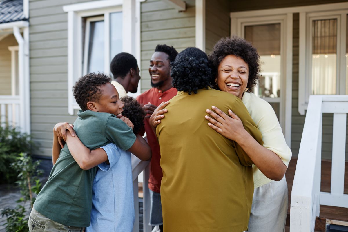 Family hugging standing on their porch 